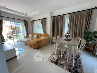Spacious living room with modern decor and dining area, featuring large windows and natural light.