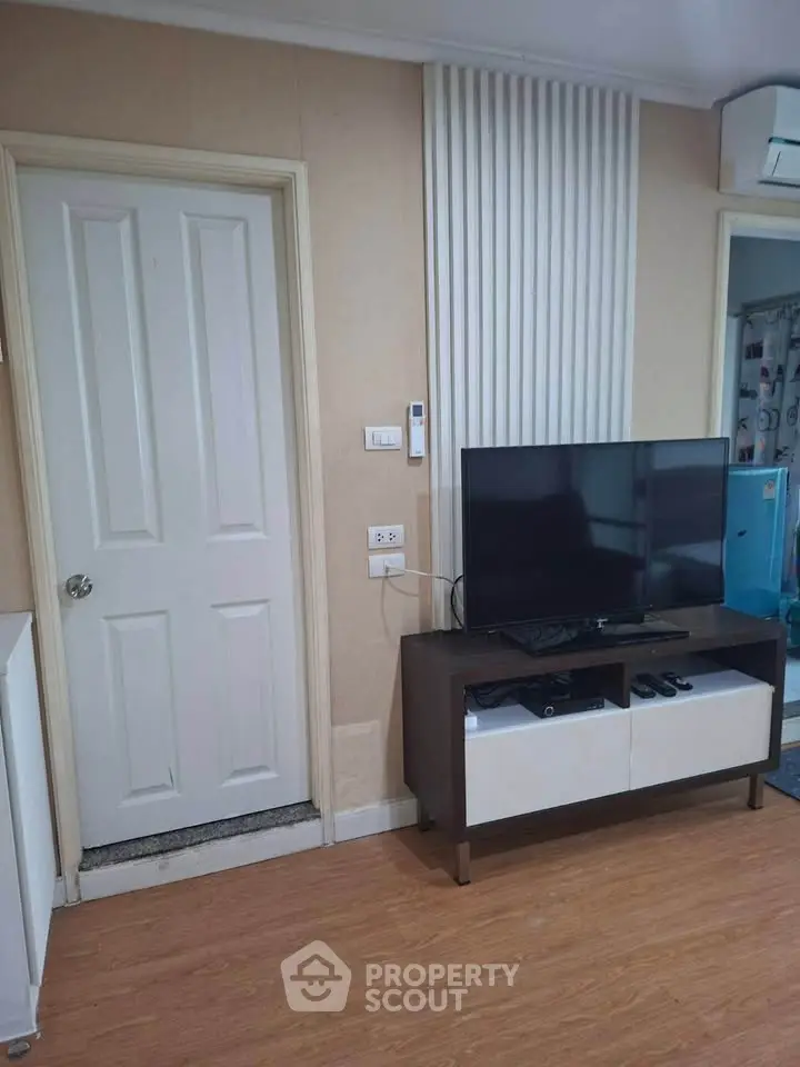 Modern living room with TV and stylish decor, featuring wood flooring and elegant wall paneling.