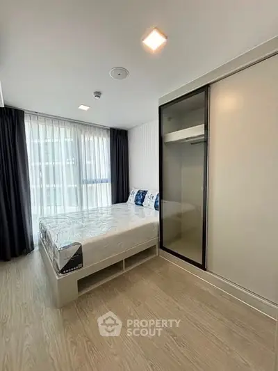 Modern bedroom with large window and sleek wardrobe in a stylish apartment.