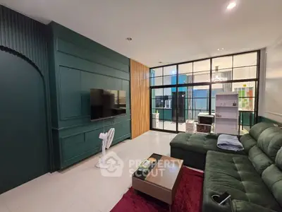 Spacious living room with modern green decor and large TV, perfect for relaxation and entertainment.