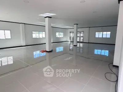 Spacious open-plan interior with glossy tiled floors and ample natural light, ideal for versatile use.