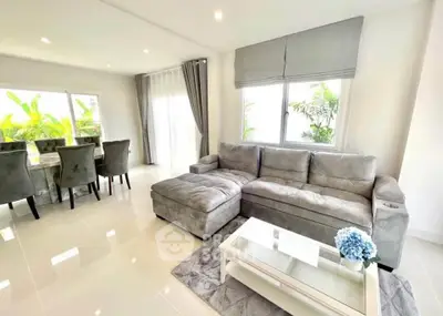 Spacious modern living room with elegant gray sofa and dining area, perfect for family gatherings.