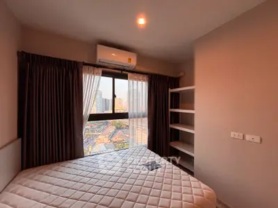 Cozy bedroom with city view, featuring a comfortable bed and built-in shelves, perfect for urban living.