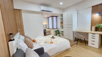 Modern bedroom with cozy decor and study area, featuring wooden accents and ample natural light.