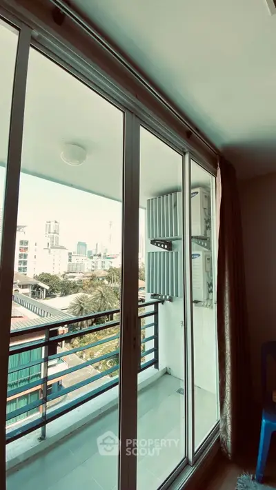 Spacious balcony with sliding glass doors offering cityscape views in modern apartment.