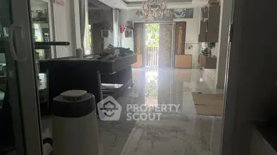 Spacious living room with marble flooring and elegant decor, featuring a chandelier and large windows for natural light.