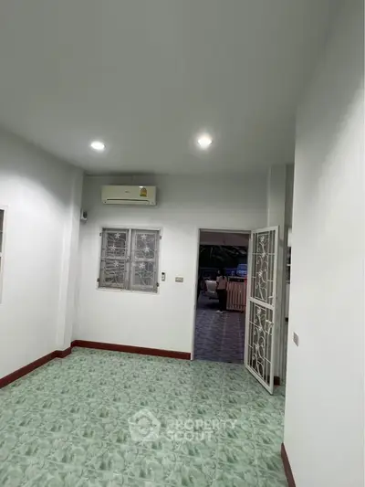 Spacious room with air conditioning and tiled floor, featuring a secure window and open door to a tiled patio.