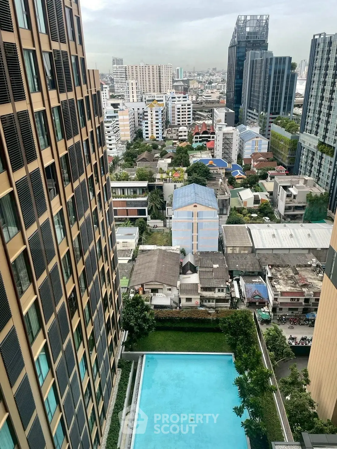 Stunning city view from high-rise apartment with pool and modern architecture.