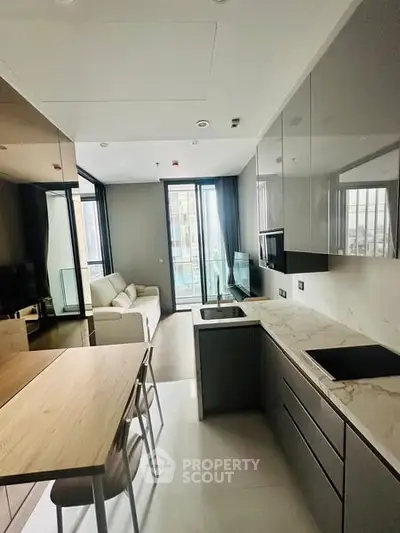 Modern open-layout kitchen with sleek cabinetry and cozy living area in a stylish apartment.