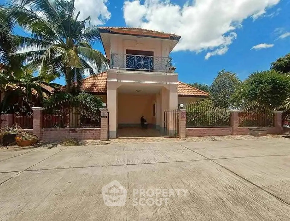 Charming two-story house with balcony and lush garden in tropical setting