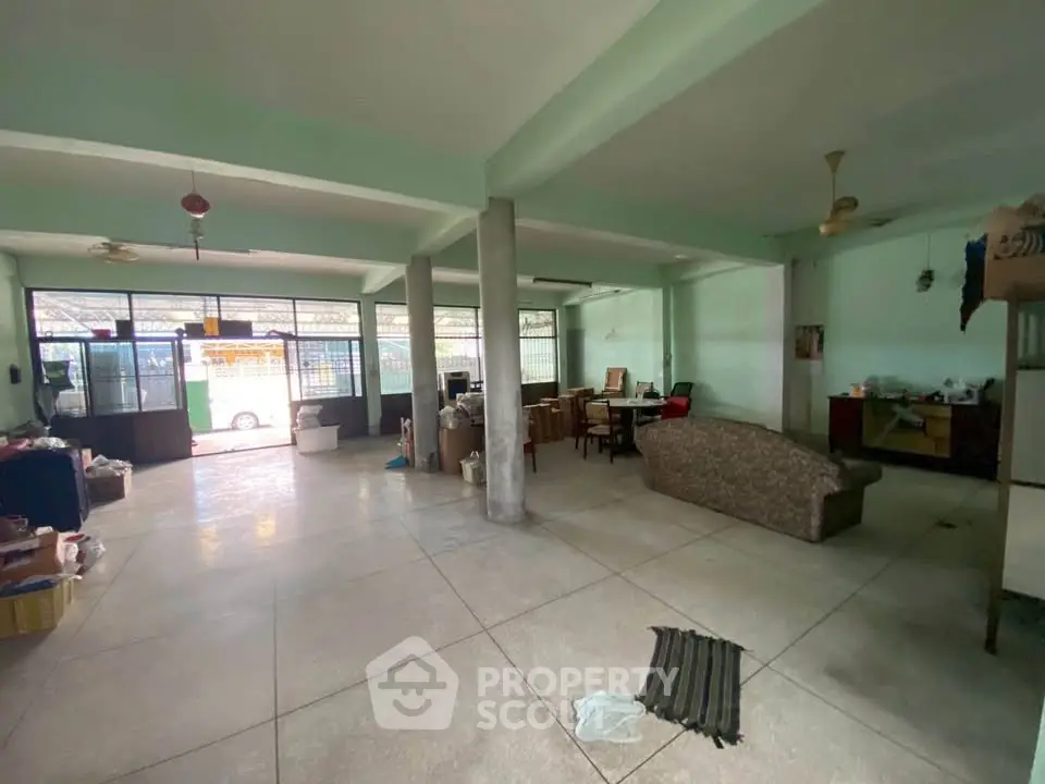 Spacious open-plan living area with large windows and tiled flooring