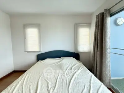 Cozy bedroom with natural light and balcony access, perfect for relaxation.