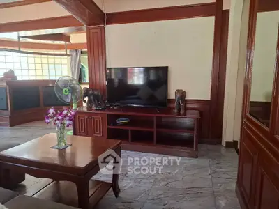 Spacious living room with elegant wooden furniture and modern TV setup.