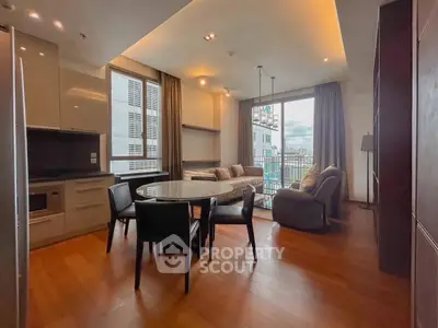 Spacious modern living room with open kitchen and city view, featuring elegant furniture and large windows.