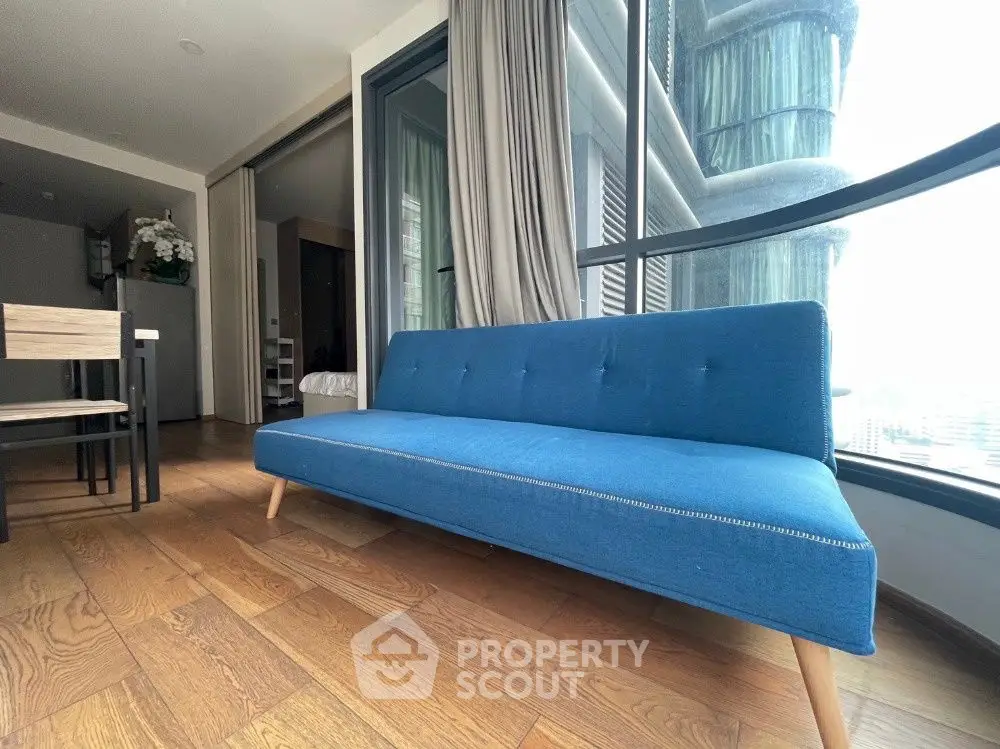 Modern living room with blue sofa and large windows offering city views