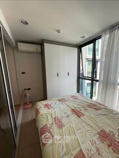 Cozy bedroom with large windows and built-in wardrobe in modern apartment