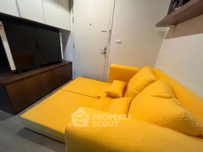 Cozy living room with vibrant yellow sofa and modern entertainment unit.