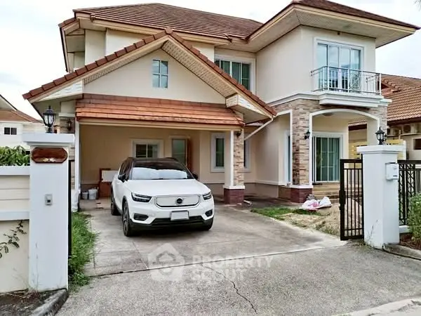 Charming two-story house with driveway and car, featuring a small balcony and elegant exterior design.