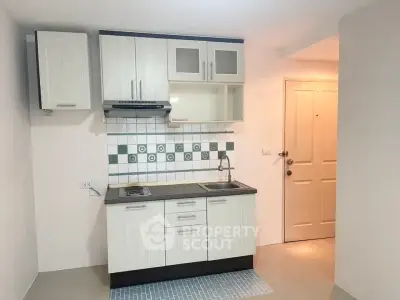 Compact kitchen with modern cabinetry and tiled backsplash in cozy apartment