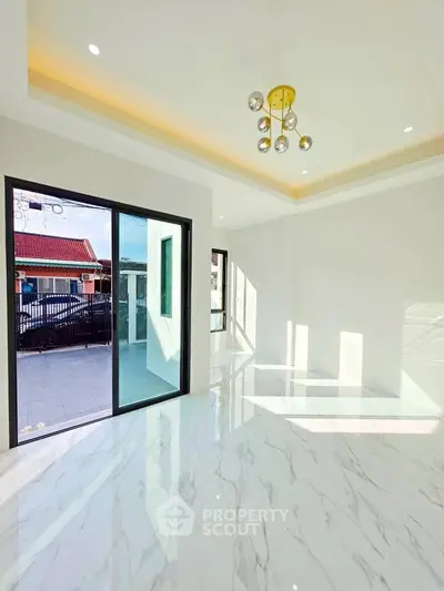 Bright modern living room with marble flooring and stylish lighting, featuring large sliding glass doors opening to a balcony.