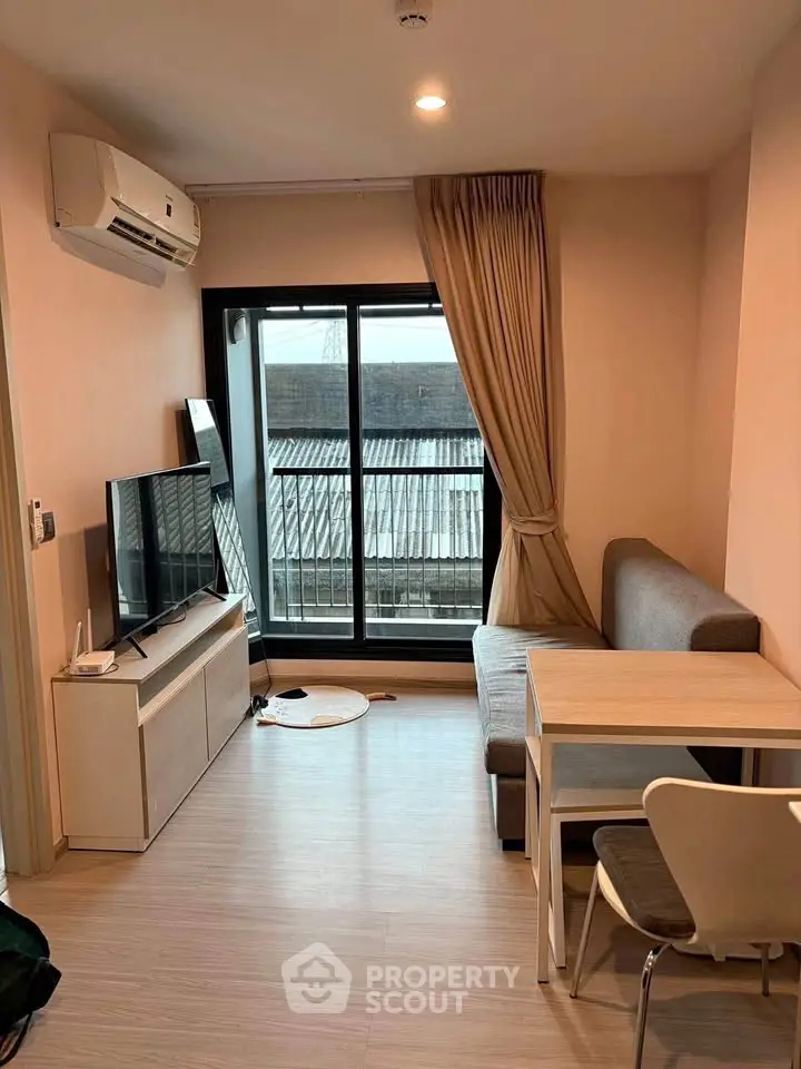 Modern living room with sleek furniture and large window offering natural light and city view.