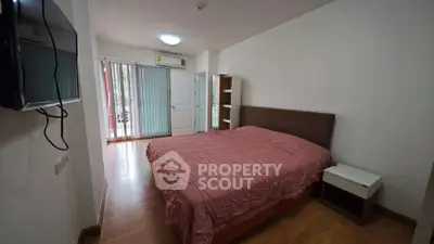 Cozy bedroom with pink bedding and natural light from balcony