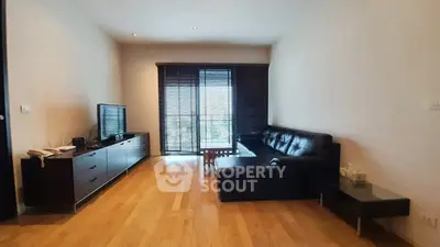 Spacious living room with modern black leather sofa and wooden flooring