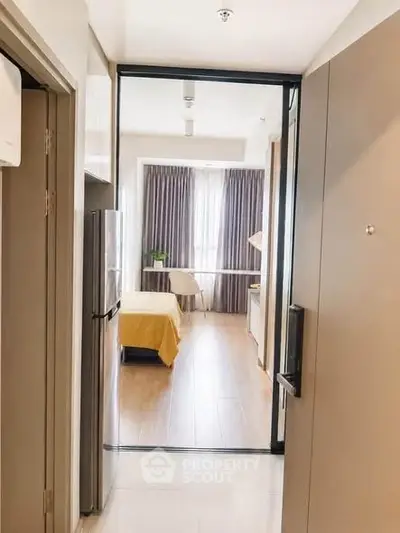 Modern apartment entrance leading to a cozy bedroom with natural light and stylish decor.