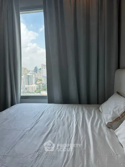 Cozy bedroom with city view through large window and elegant curtains.