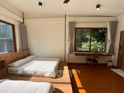 Spacious bedroom with large windows and natural light, featuring a cozy bed and a study area.