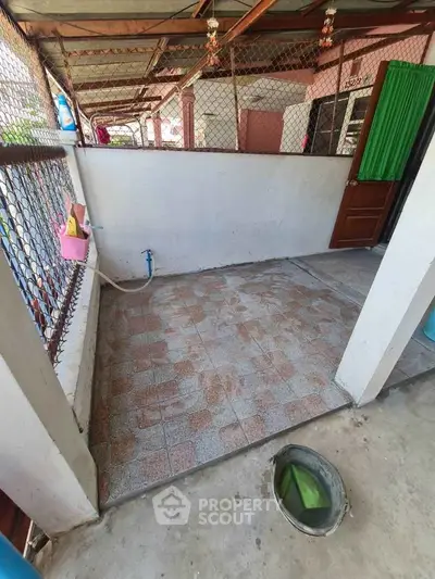 Cozy outdoor area with tiled flooring and open fencing, perfect for small gatherings.