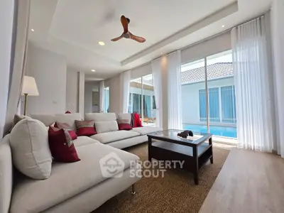 Spacious living room with pool view, modern decor, and large windows for natural light.