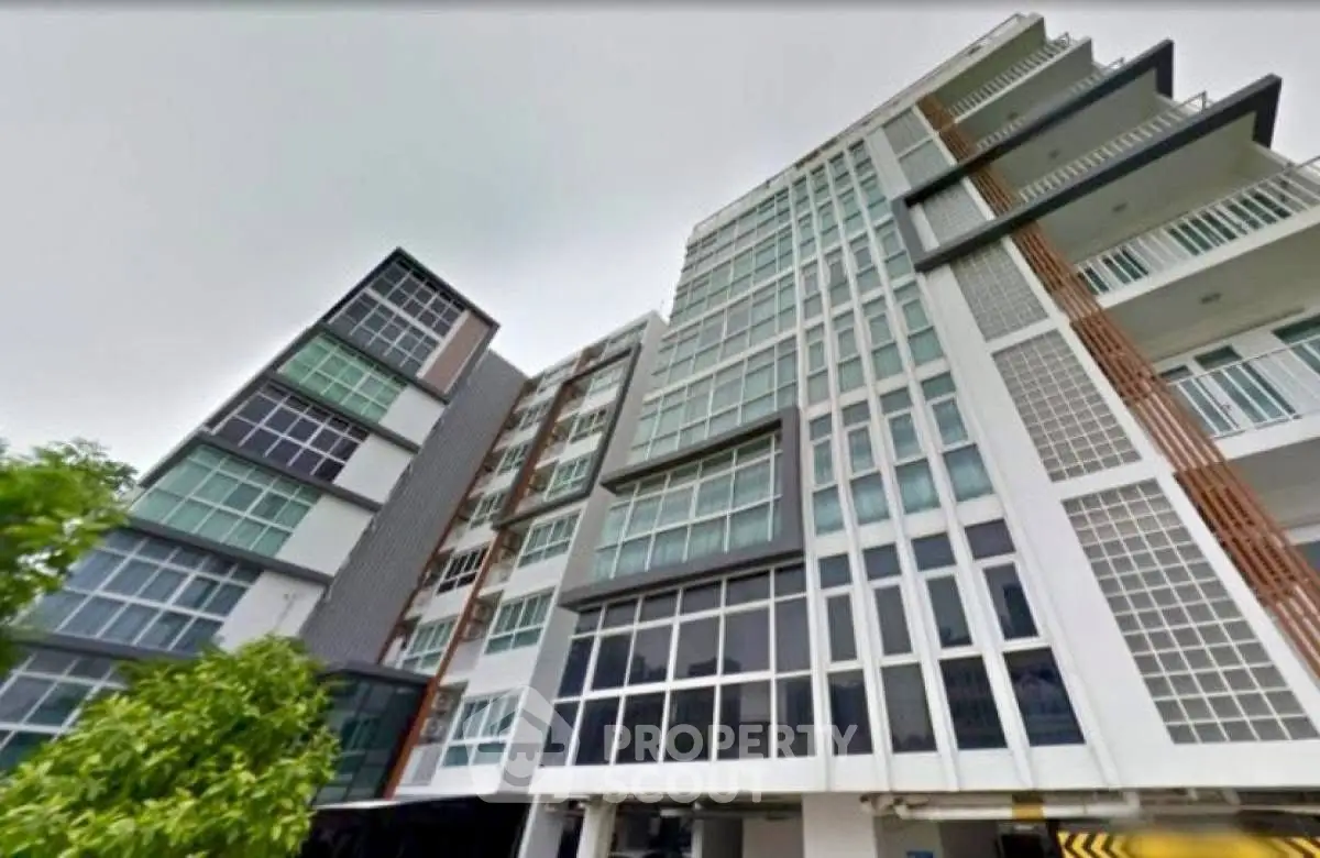 Modern multi-story apartment building with sleek glass facade and contemporary design.