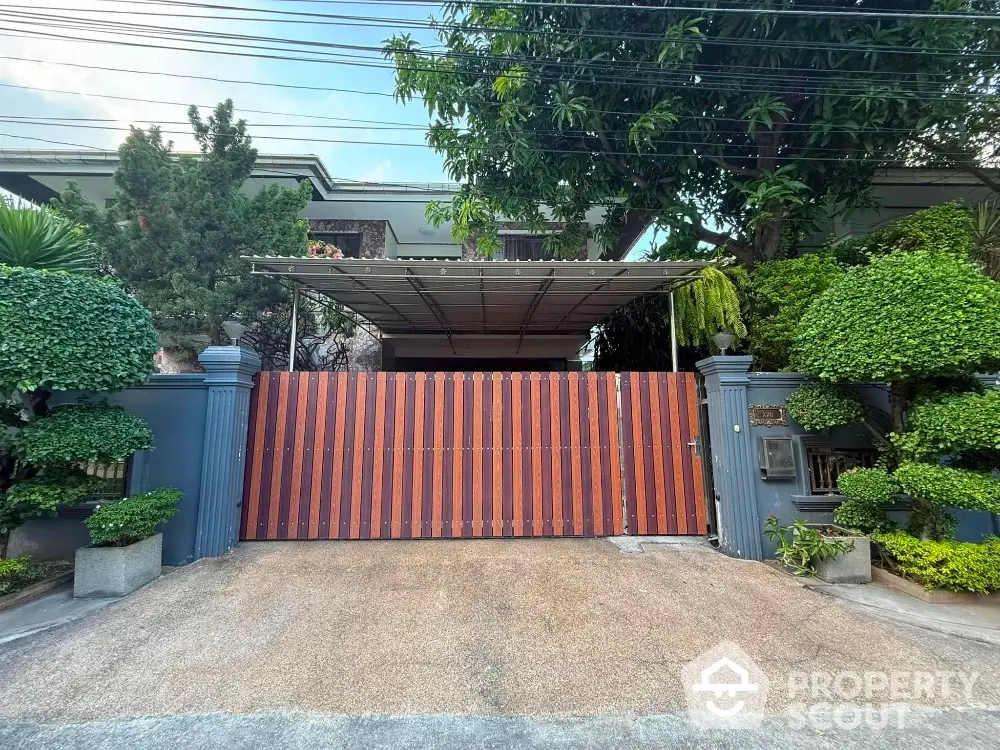 Charming residential entrance with lush greenery and secure wooden gate