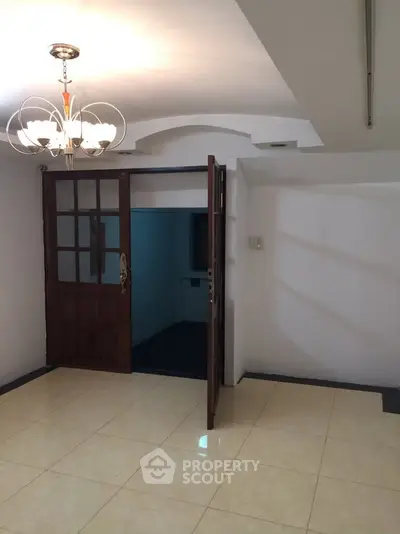 Spacious interior with elegant chandelier and tiled flooring, perfect for modern living.