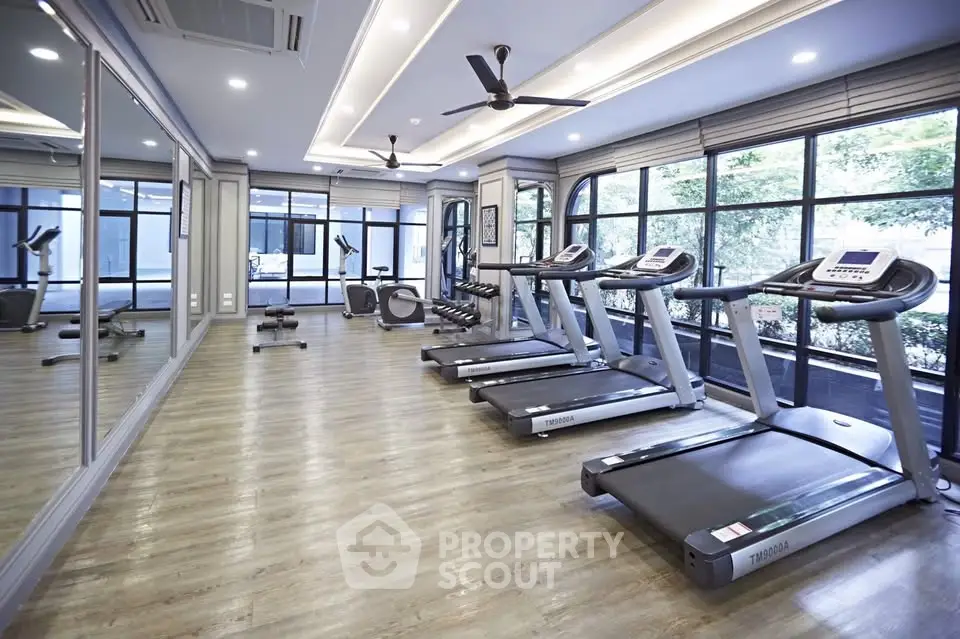 Modern gym with treadmills and large windows in a luxury residential building.