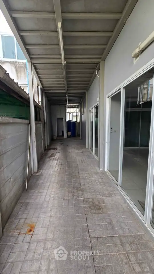 Spacious covered outdoor corridor with sliding glass doors and tiled flooring, ideal for versatile use.
