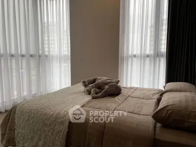 Cozy bedroom with plush bedding and large windows offering natural light.
