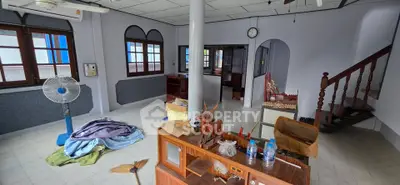 Spacious living room with staircase and large windows in a charming home.