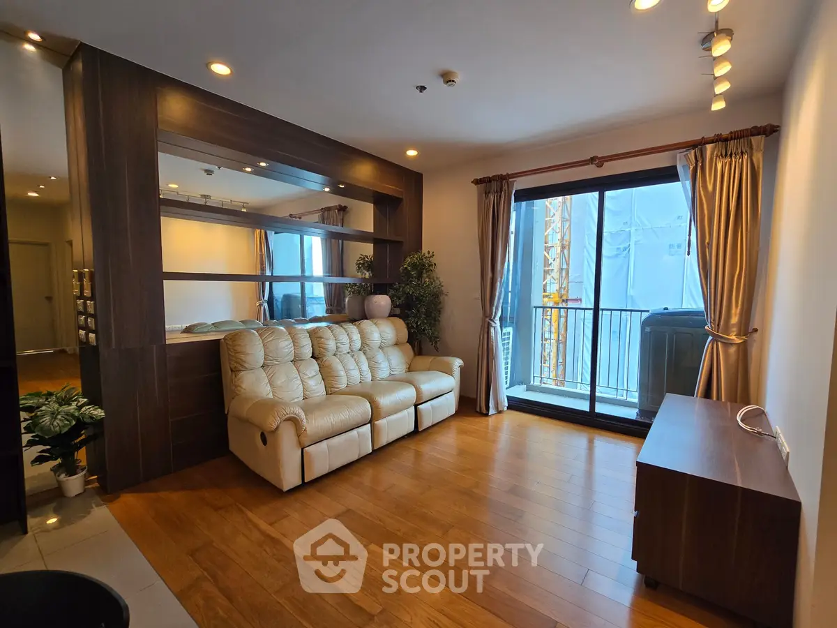 Spacious living room with elegant wooden flooring and large windows offering natural light.