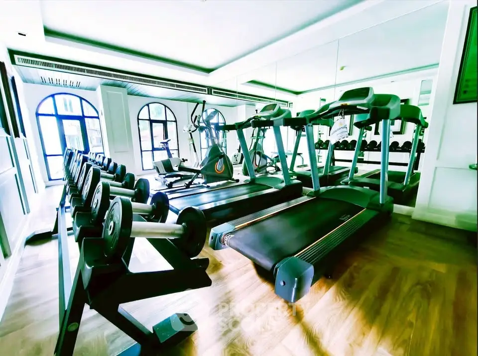 Luxurious gym with modern equipment and mirrored walls in upscale residential building.