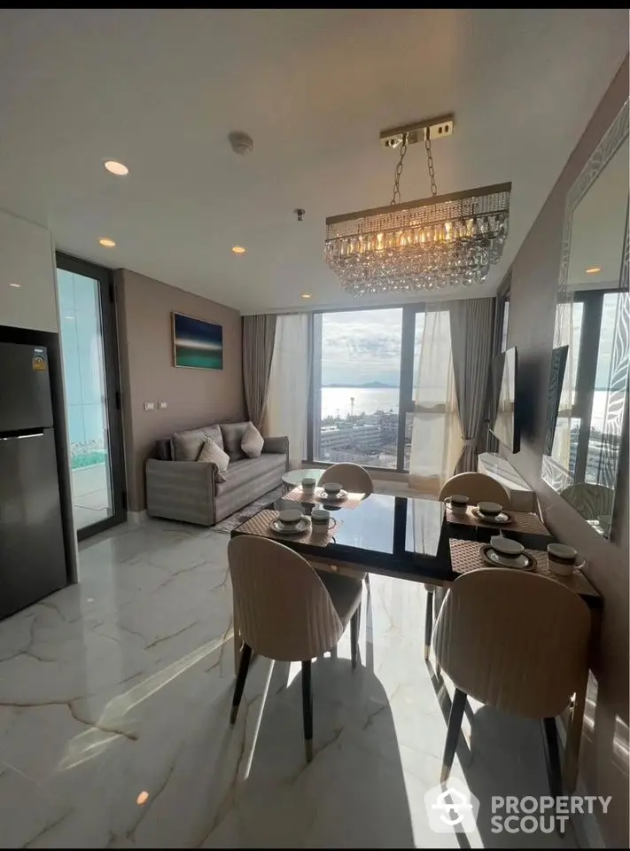 Luxurious living room with ocean view, elegant chandelier, and modern dining area.