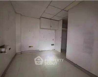 Spacious empty room with tiled flooring and ceiling panels, ideal for customization.