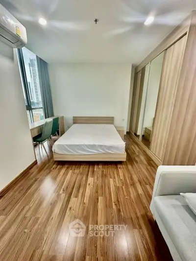 Spacious bedroom with wooden flooring and large window in modern apartment