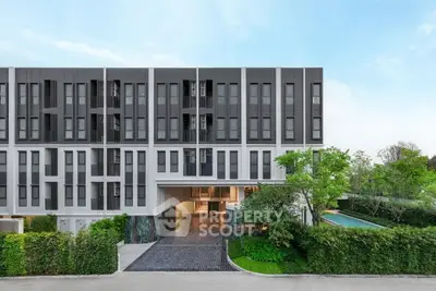 Modern apartment building exterior with lush greenery and clear blue sky