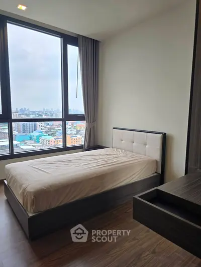Modern bedroom with large window offering stunning city views, featuring sleek furniture and elegant design.