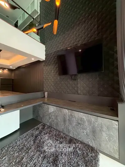 Modern living room with stylish decor, featuring a large TV and elegant wall textures.