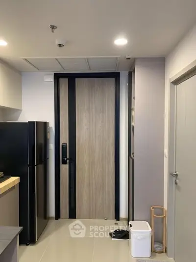 Modern apartment entrance with sleek black refrigerator and stylish wooden door