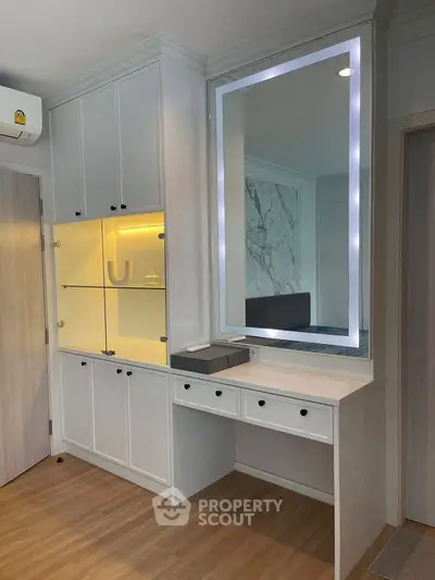 Modern bedroom with built-in storage and illuminated mirror, showcasing sleek design and functionality.