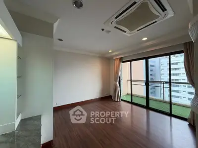Spacious living room with wooden flooring and balcony access in modern apartment